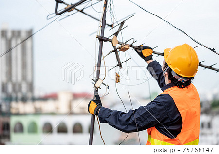 Asian worker repairing an old TV antenna on rooftop 75268147