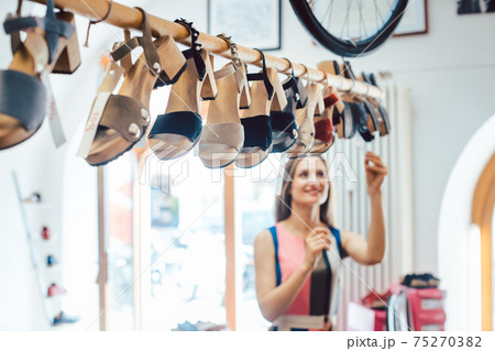 Woman looking at shoes dangling from the ceiling in store Woman looking at shoes dangling from the ceiling in store 75270382