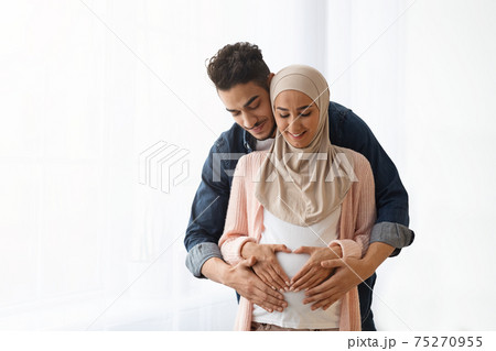 Portrait of young religious muslim couple expecting baby bonding at home Portrait of young religious muslim couple expecting baby bonding at home 75270955