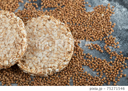 Two crispbread and uncooked buckwheat on marble surface 75271546