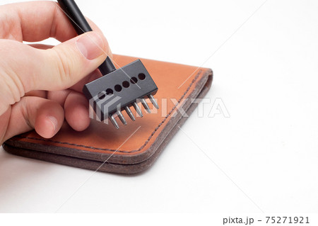 Working process of the leather wallet. Man holding punching tool 75271921