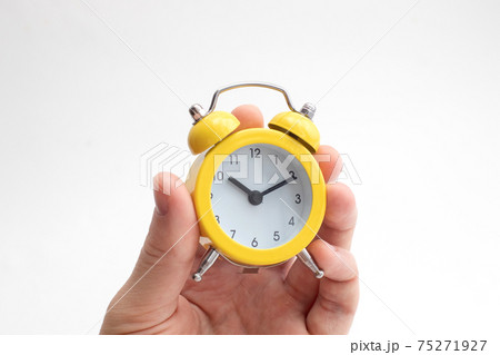 Hand holding yellow alarm clock on light background. Time concept. Keep your time Hand holding yellow alarm clock on light background. Time concept. Keep your time 75271927