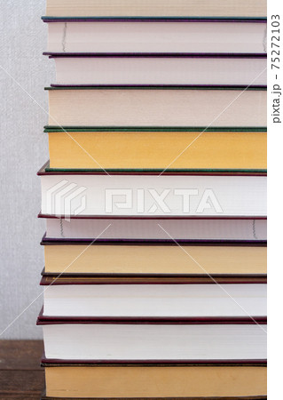 A vertical of stack of books on a wooden shelf and a gray background A vertical of stack of books on a wooden shelf and a gray background 75272103