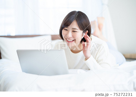 女性 うつ伏せ パソコン 寝室の写真素材