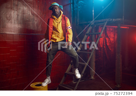 Stylish rapper poses on stairs in grunge studio 75272394