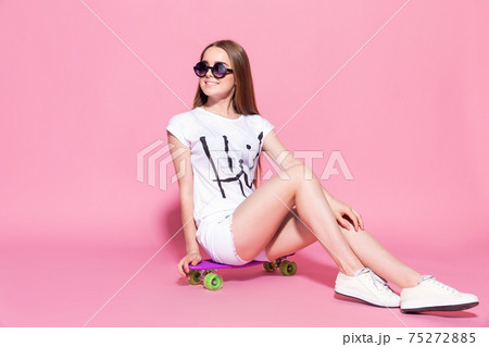 Cheerful young girl with a skateboard on the pink background 75272885