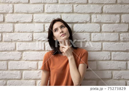 Thoughtful young teen female look up touch chin make choice 75273829