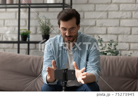 Confident male coach sit on sofa before smartphone record training Confident male coach sit on sofa before smartphone record training 75273945