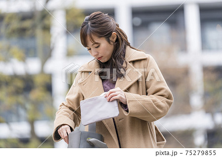 マスクポーチからマスクを出す女性 75279855