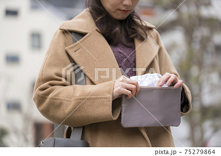 マスクポーチからマスクを出す女性 75279864