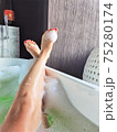 Two crossed legs in the bathtub and green water bubbles 75280174