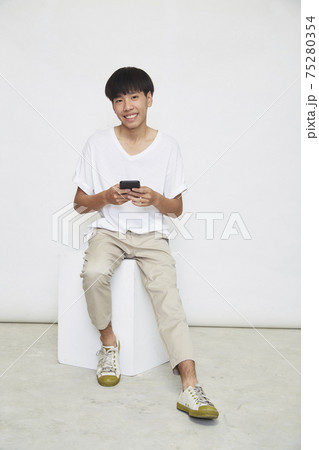 Asian guy sit and use the phone Asian guy sit and use the phone 75280354