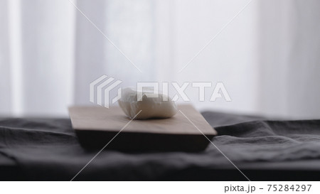 sliced mozzarella ball on olive wood board with window on background 75284297