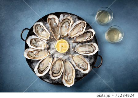 Oysters on ice, lemon, and white wine, overhead flat lay shot 75284924