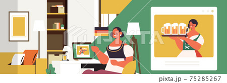 Oktoberfest party celebration woman with beer mugs discussing with girl in traditional clothes during video call 75285267