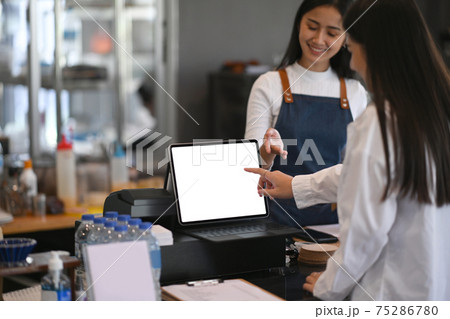 Young woman coffee shop owner working behind the counter bar recommending menu and receiving orders from customers. Young woman coffee shop owner working behind the counter bar recommending menu and receiving orders from customers. 75286780