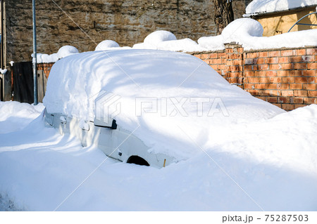 Car under a thick layer of snow after heavy snowfall 75287503