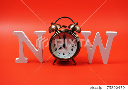 Now alphabet letters with alarm clock on red background Now alphabet letters with alarm clock on red background 75290470