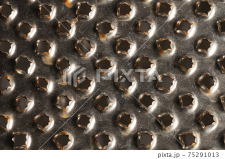 Close-up pattern of the holes of an old kitchen grater with rust elements. Grunge background 75291013