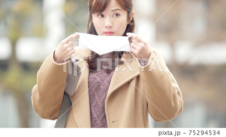 マスクポーチからマスクを出す女性 75294534