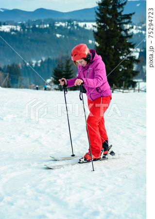 Photo of young smiling sportswoman in ski helmet in hand against blue sky and snowy hill and picturesque Carpathians. Photo of young smiling sportswoman in ski helmet in hand against blue sky and snowy hill and picturesque Carpathians. 75294723