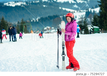 Woman stands on top of mountain in ski outfit, on sky and mountains background. Woman stands on top of mountain in ski outfit, on sky and mountains background. 75294727
