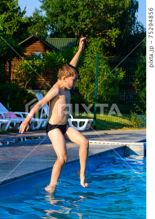The boy jumps into the pool, children's games and entertainment in the aqua park. The boy jumps into the pool, children's games and entertainment in the aqua park. 75294856