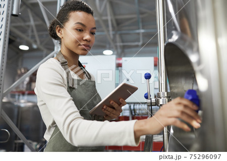 Young Female Worker Opening Valve at Factory Young Female Worker Opening Valve at Factory 75296097