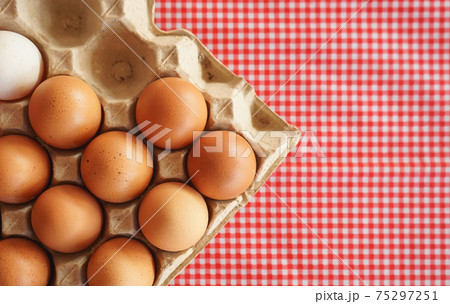 Flat lay of chicken eggs in carton box on classic pink tablecloth Flat lay of chicken eggs in carton box on classic pink tablecloth 75297251
