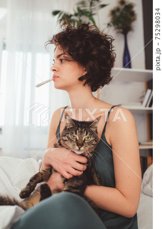 Woman is holding in her arms cute striped cat with big green eyes Woman is holding in her arms cute striped cat with big green eyes 75298034