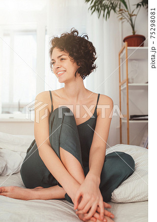 Woman feeling happiness while spending her weekend at home and smiling Woman feeling happiness while spending her weekend at home and smiling 75298081