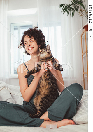 Beautiful middle-aged woman sitting at home on the bed and laughing 75298105