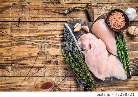 Fresh Raw sliced cut chicken breast fillet steaks on a wooden cutting board with kitchen knife. wooden background. Top view. Copy space 75298721