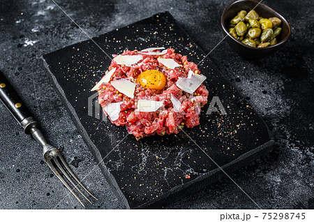 Tartar beef with a quail egg, capers and Parmesan cheese. Black background. Top view 75298745