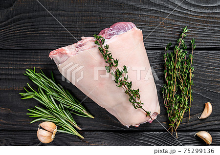 Raw Pork knuckle leg meat on kitchen table with herbs. Black wooden background. Top view Raw Pork knuckle leg meat on kitchen table with herbs. Black wooden background. Top view 75299136