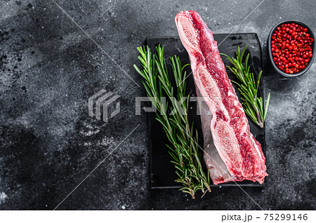 Raw beef short ribs kalbi on marble board. Black background. Top view. Copy space 75299146