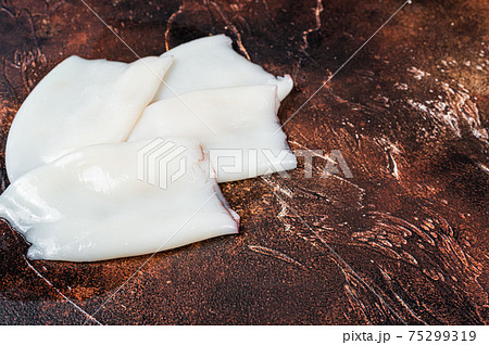 Raw Squid or Calamari tubes on a kitchen table. Dark background. Top view. Copy space Raw Squid or Calamari tubes on a kitchen table. Dark background. Top view. Copy space 75299319