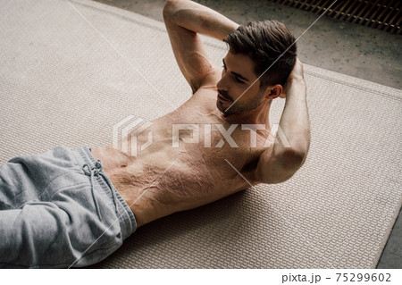 Man with scars at the skin after burn practicing abdominal crunches, rock press exercise Man with scars at the skin after burn practicing abdominal crunches, rock press exercise 75299602
