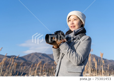 自然の中でデジタル一眼レフカメラを持つ女性の写真素材