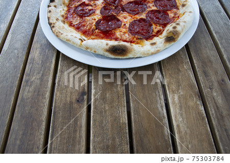 Pepperoni pizza on a wooden table. 75303784