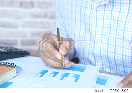 man hand with pen analyzing bar chart on paper man hand with pen analyzing bar chart on paper 75304302
