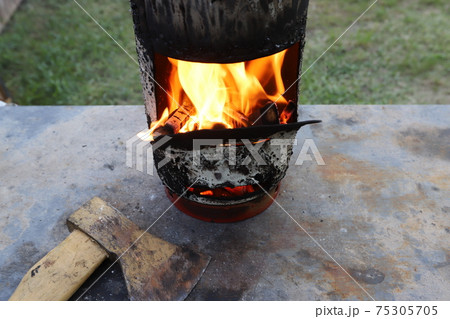 Burning firewood with a bright flame in an iron grill after setting fire to frying meat kebabs. A picnic in a forest glade	 75305705