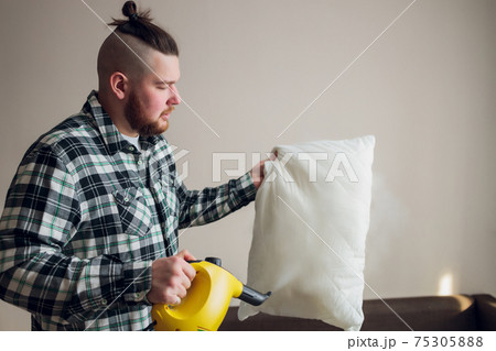 Dry cleaning worker removing dirt from sofa cushion indoors. 75305888