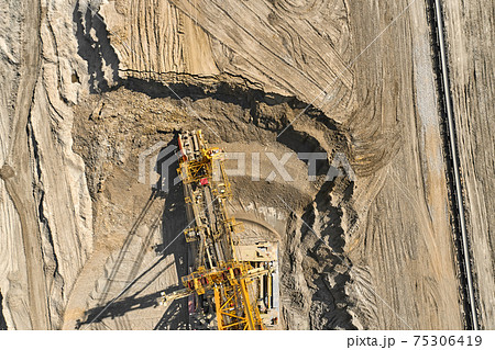 Aerial view of large heavy equipment machine mining natural resource. Coal mining by bucket wheel excavator. Heavy industry Aerial view of large heavy equipment machine mining natural resource. Coal mining by bucket wheel excavator. Heavy industry 75306419