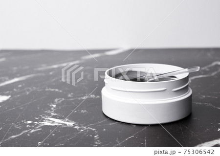 A white jar with eye patches and spatula on the marble table with copy space. 75306542