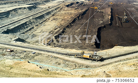Panoramic view of a quarry with huge machine, bucket wheel excavator mining a coal. Heavy industry Panoramic view of a quarry with huge machine, bucket wheel excavator mining a coal. Heavy industry 75306652