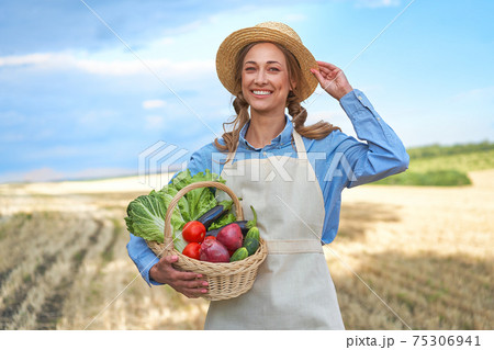 Woman farmer straw hat apron standing farmland smiling Female agronomist specialist farming agribusiness Happy positive caucasian worker agricultural field Woman farmer straw hat apron standing farmland smiling Female agronomist specialist farming agribusiness Happy positive caucasian worker agricultural field 75306941