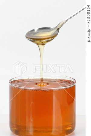 ミツバチが作った甘いはちみつをスプーンですくいました。 75308154