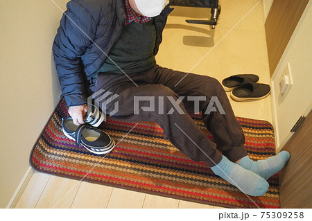 床に座り介護シューズを履く老人男性1 75309258