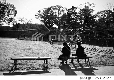 公園のベンチに座るカップルのシルエットの写真素材
